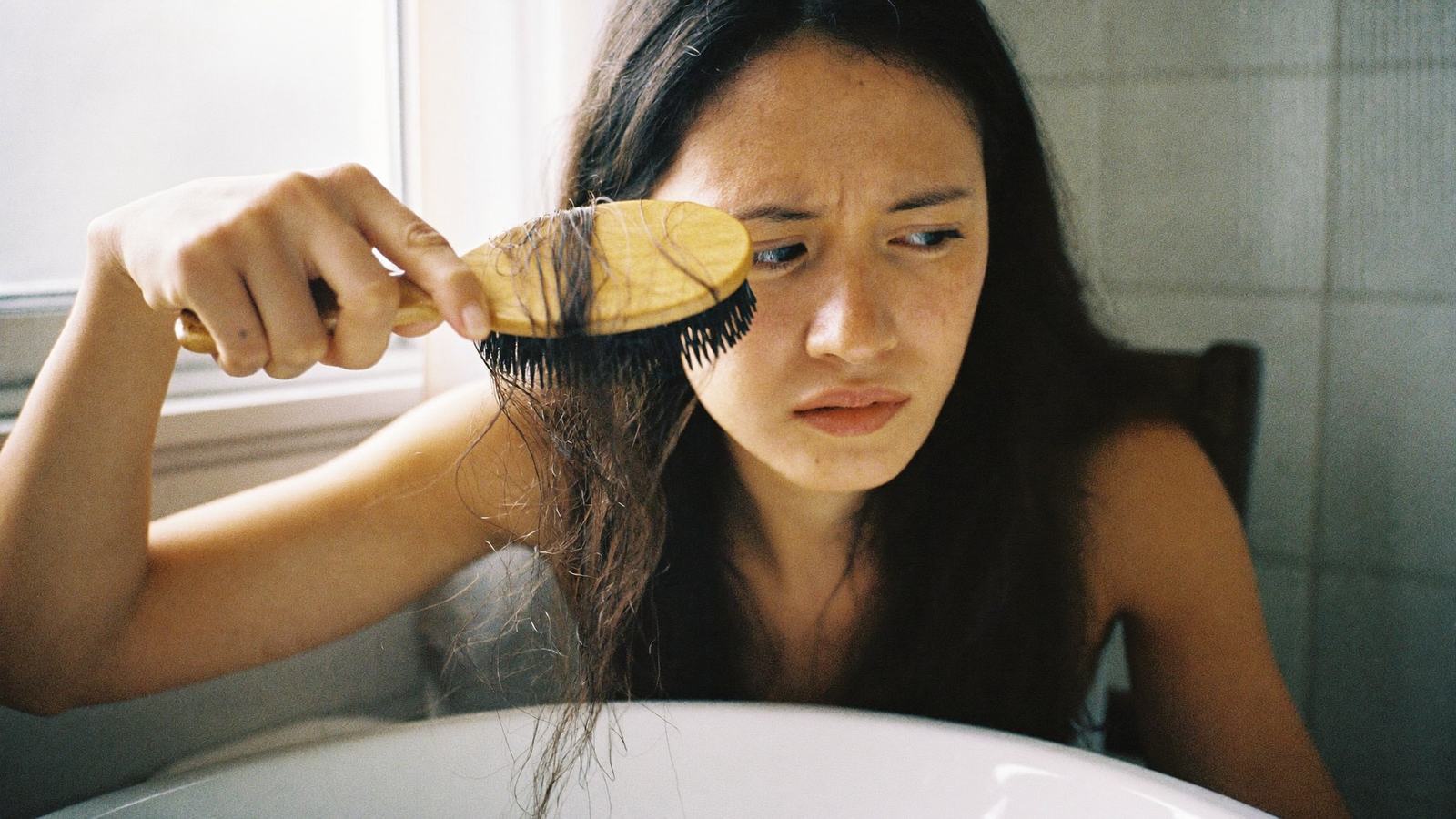 Người phụ nữ lo lắng nhìn tóc rụng nhiều trên lược