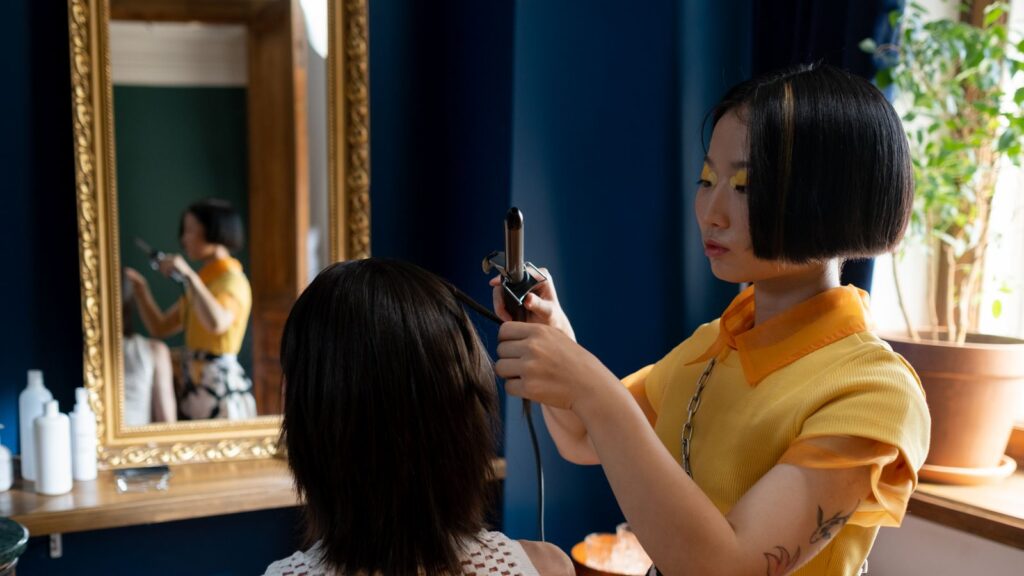 Thợ tóc người Việt tư vấn chăm sóc tóc cho khách nữ tại salon, quan sát tình trạng tóc để gợi ý sản phẩm phù hợp