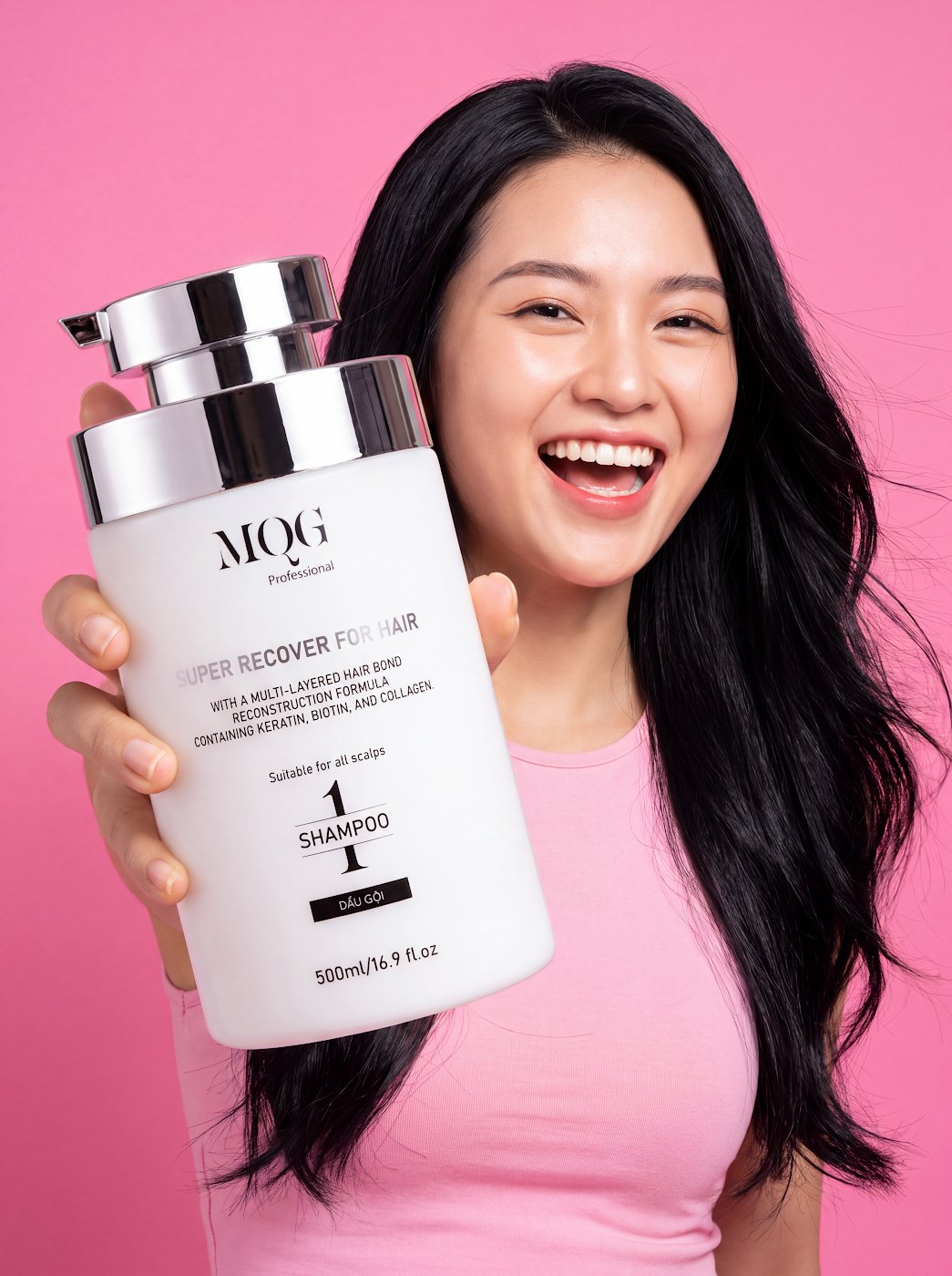 Cô gái cười tươi cầm chai dầu gội MQG, mái tóc dày bồng bềnh