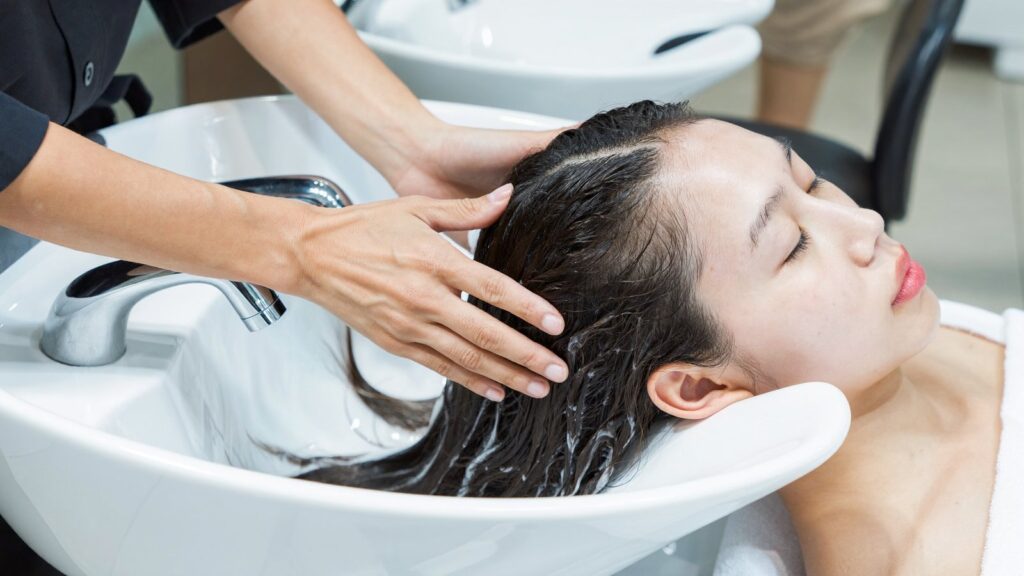 Thợ tóc massage da đầu khi làm sạch sâu tại bồn gội salon